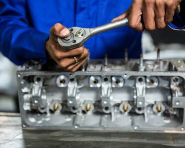 Mid-section of mechanic repairing engine part with ratchet at the repair garage