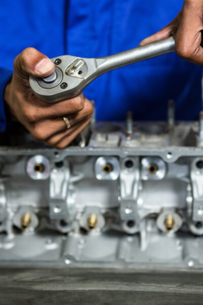 Mid-section of mechanic repairing engine part with ratchet at the repair garage
