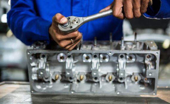 Mid-section of mechanic repairing engine part with ratchet at the repair garage