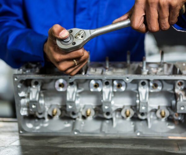 Mid-section of mechanic repairing engine part with ratchet at the repair garage