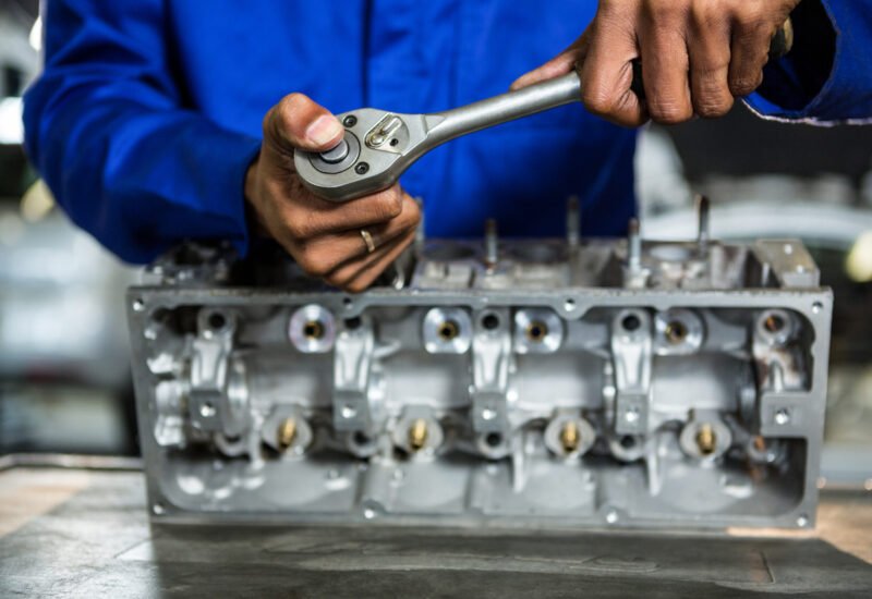 Mid-section of mechanic repairing engine part with ratchet at the repair garage